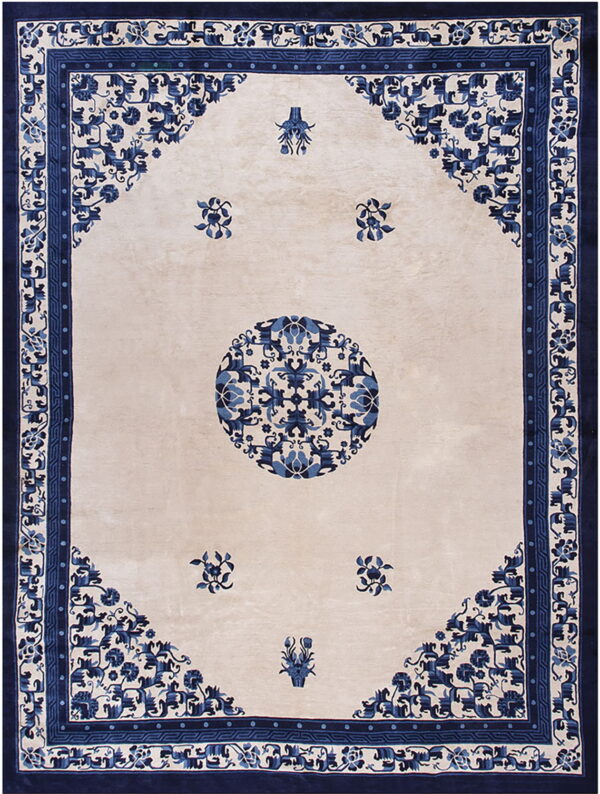 Rectangular cream rug featuring a central blue medallion and intricate navy floral patterns in the corners and border.