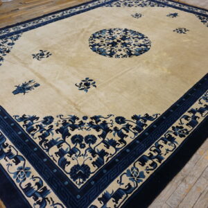 Large cream rug with indigo floral pattern and wide border rests on rustic wood floors.