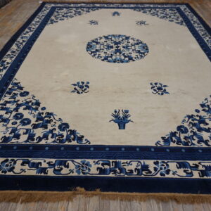 A large blue and cream rug with a medallion and floral borders rests on wood plank flooring.