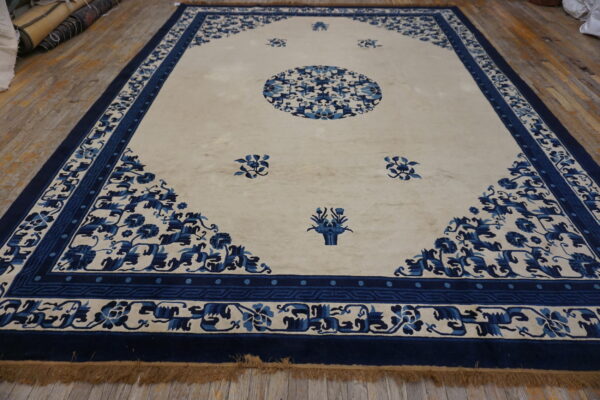 A large blue and cream rug with a medallion and floral borders rests on wood plank flooring.