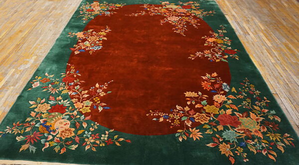 Ornate floral rug with a deep reddish-brown central field surrounded by a wide green border.