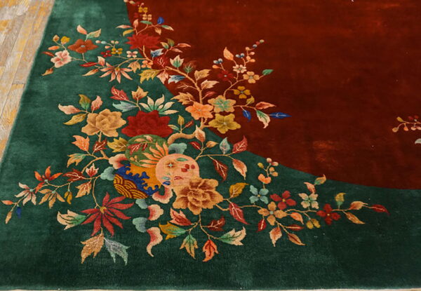 High-pile green and red rug featuring detailed vines, leaves, and large multicolored blossoms on wood planks.