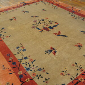 Khaki rug with a multi-banded orange and red border, featuring stylized blue and red birds and floral branches.