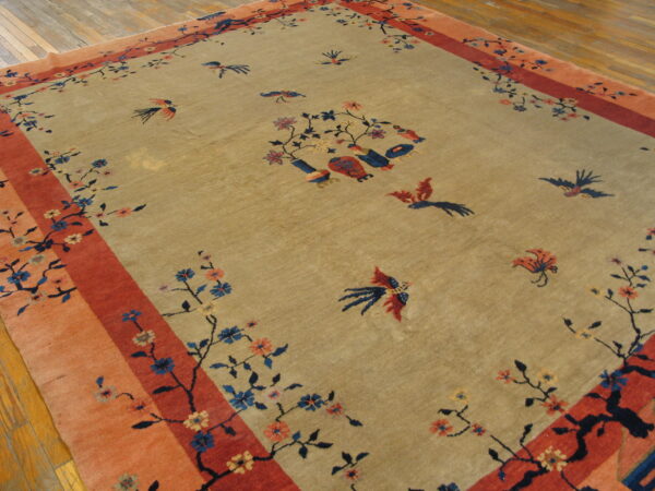 Khaki rug with a multi-banded orange and red border, featuring stylized blue and red birds and floral branches.