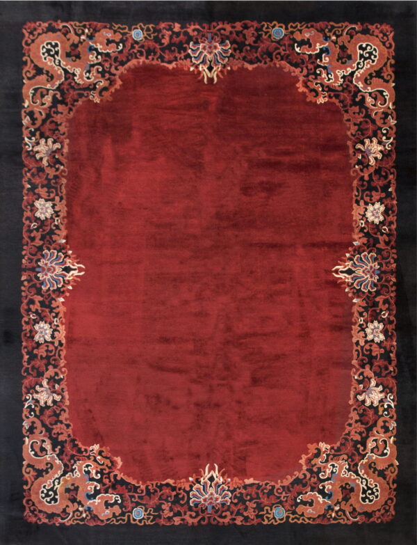 High-pile red rug with an elaborately scrolled black border patterned with stylized orange dragons and flowers.