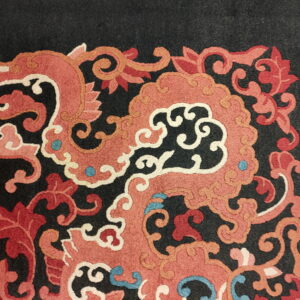 Ornate scrolling coral and red patterns with cream outlines and blue accents on a black rug field.