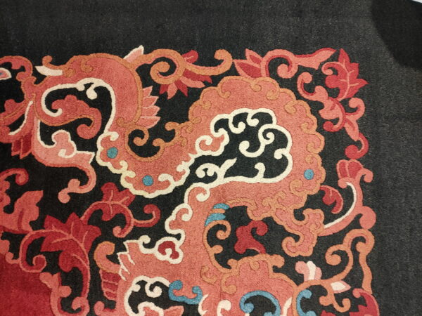 Ornate scrolling coral and red patterns with cream outlines and blue accents on a black rug field.