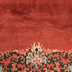 Deep red rug detail showing a multicolored floral border on a dark charcoal background.