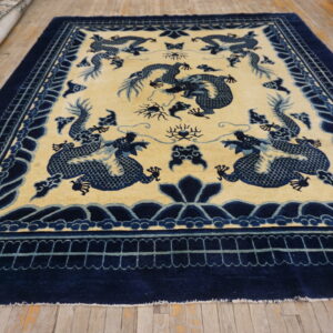 Blue dragon motifs dominate the cream central field and bordered navy design of this rug on wood flooring.
