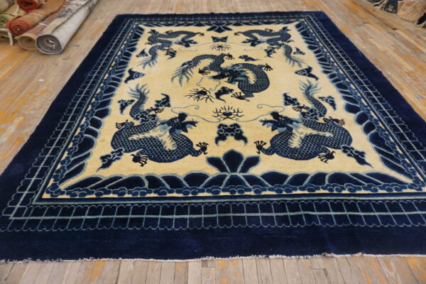 Blue dragon motifs dominate the cream central field and bordered navy design of this rug on wood flooring.