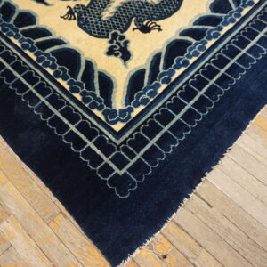 Navy blue rug border and cream field with teal outlines resting on rustic, light-colored wood planks.