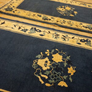 Navy rugs with contrasting gold borders and large floral medallions lie on light wood planks.