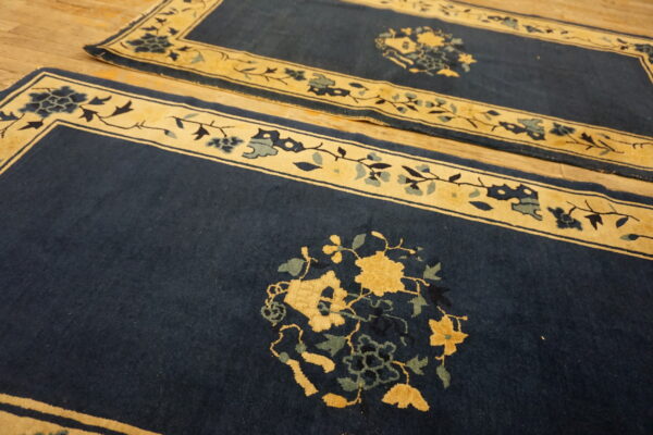 Navy rugs with contrasting gold borders and large floral medallions lie on light wood planks.