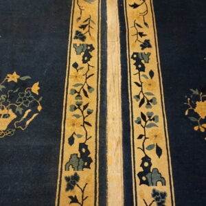 Deep blue rug with gold vertical floral stripes and central yellow flower motifs on a wood floor.