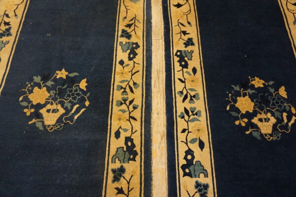 Deep blue rug with gold vertical floral stripes and central yellow flower motifs on a wood floor.
