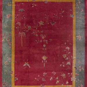 Red field rug with a sage border featuring sprawling multi-colored floral and butterfly designs.