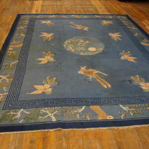 Large blue rug featuring colorful scattered bird patterns, geometric borders, and a central medallion on wood flooring.