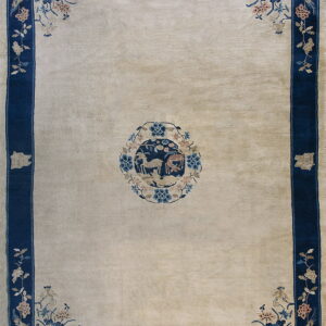 Cream rug with a navy blue border, corner florals in blue and pink, and a central animal motif.