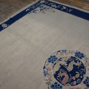 Low pile beige rug featuring a navy border with floral vines and a stylized blue and pink animal medallion.