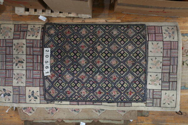 Overhead view of a gray-blue floral rug with a contrasting cream, red, and striped square border on wood flooring.