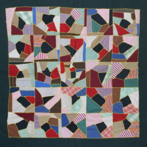 Multi-colored patchwork textile features irregular fabric shapes stitched together with bright yellow zig-zag trim and a dark green border.