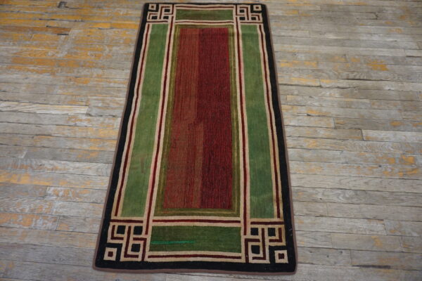 Geometric runner rug in red, green, black, and beige on weathered gray wood flooring.