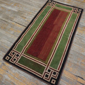 A red and green geometric runner rug with a striped texture rests on heavily distressed wood flooring.