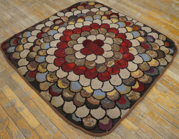 Textured, multicolor diamond rug with loop-pile pebble shapes and a red center on yellow wood flooring.