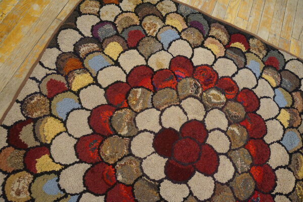 Textured loop rug with multicolored overlapping scale patterns resting on yellow wood planks.