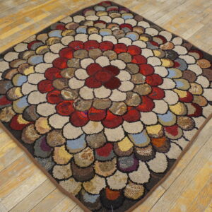 Round-edged diamond rug with multicolored hooked scallop patterns rests on rustic wood flooring.