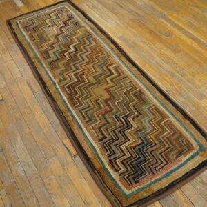 Multicolor zig-zag patterned runner rug with a striped border resting on distressed wood planks.