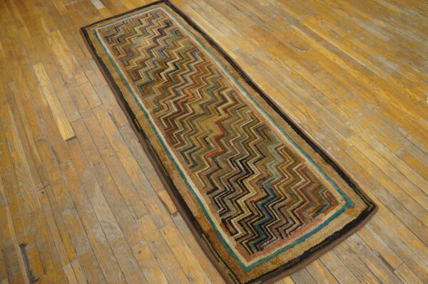 Multicolor zig-zag patterned runner rug with a striped border resting on distressed wood planks.