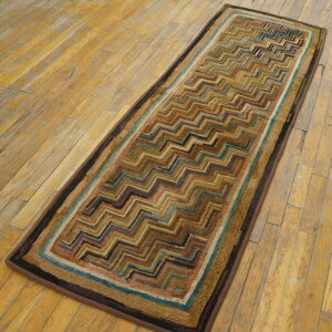 A textured runner with brown, teal, and black zigzag patterns rests on light brown distressed wood flooring.