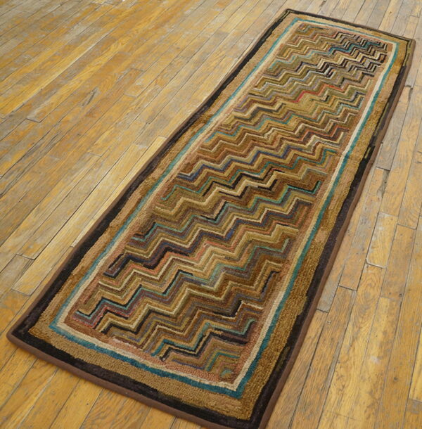 A textured runner with brown, teal, and black zigzag patterns rests on light brown distressed wood flooring.
