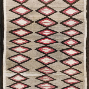 A gray flatwoven textile with vertical rows of dark brown, pink, and white layered diamond shapes.