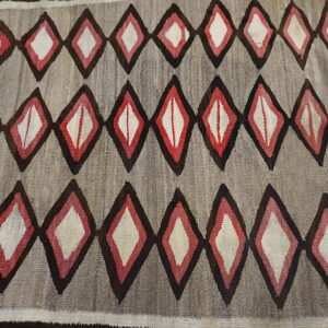 Gray flatweave rug patterned with rows of repeating concentric diamonds in dark brown, red, and cream colors.