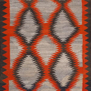 Low-pile rug with interlocking red and black serrated diamond patterns on a grey field and dark borders.