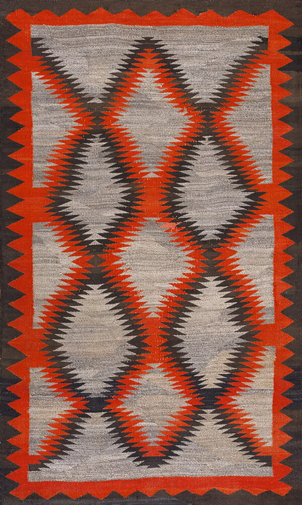 Low-pile rug with interlocking red and black serrated diamond patterns on a grey field and dark borders.