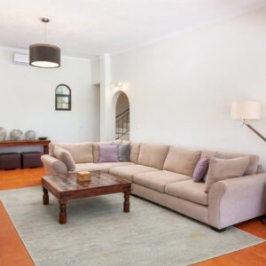 A dark teal geometric rug anchors a bright living room with a cream boucle sofa and wood herringbone floors.