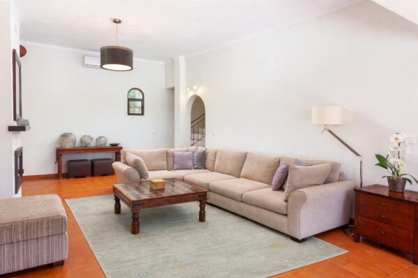 A dark teal geometric rug anchors a bright living room with a cream boucle sofa and wood herringbone floors.