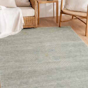 A striated dark teal rug with a dotted pattern lies on wood flooring surrounded by wicker furniture.