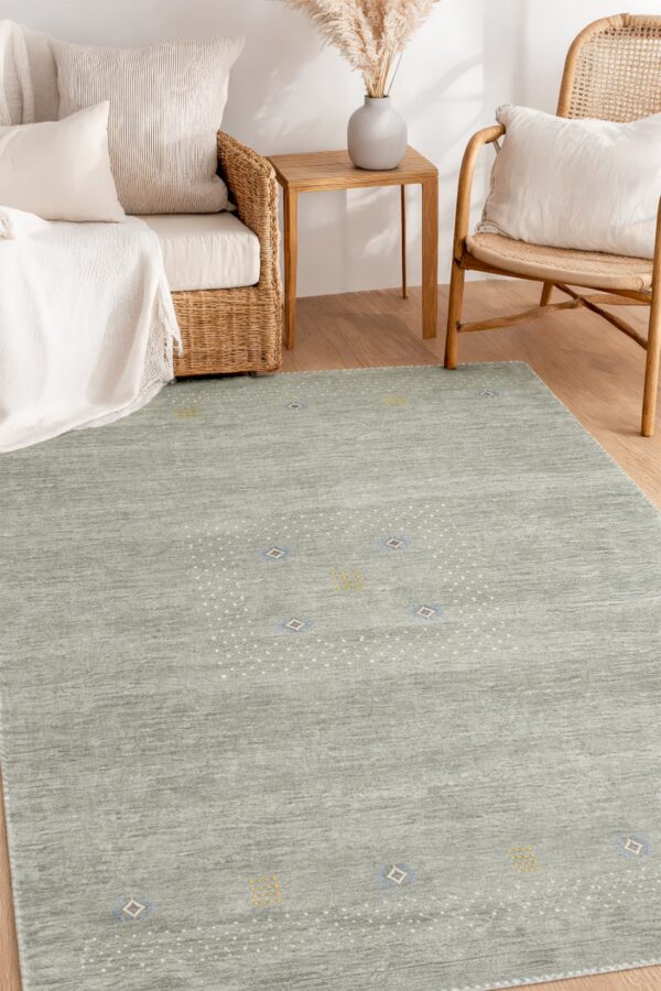 A striated dark teal rug with a dotted pattern lies on wood flooring surrounded by wicker furniture.