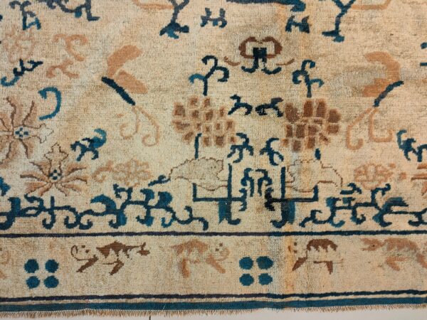 Textured rug detail with stylized floral and geometric patterns in beige, teal blue, and brown colors.