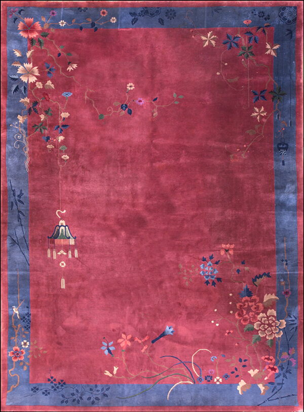 Berry red rug with a dusty blue border featuring colorful trailing florals and vines around an open field.