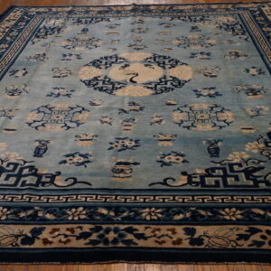 Light blue rug with dark blue and beige traditional floral patterns, a central crane, on a wood floor.
