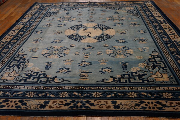 Light blue rug with dark blue and beige traditional floral patterns, a central crane, on a wood floor.
