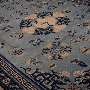 Light blue rug featuring navy geometric borders, scattered tan floral motifs, and a central crane design.
