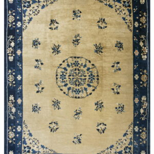 A traditional rug with a tan field, scattered blue floral sprays, and a wide navy blue border.