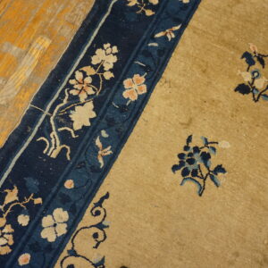 Gold field and navy border rug with cream and pink floral motifs on aged hardwood planks.