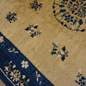 Golden beige rug featuring scattered blue floral motifs and a detailed navy blue border on wooden flooring.